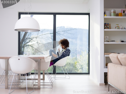 Image of black woman drinking coffee and using a mobile phone  at home