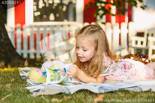 Image of Cute Little Blond Girl Reading Book Outside on Grass