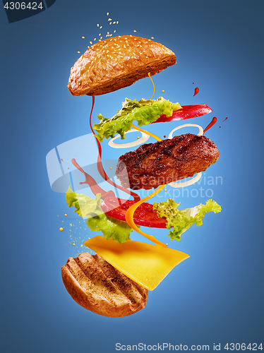 Image of The hamburger with flying ingredients on blue background