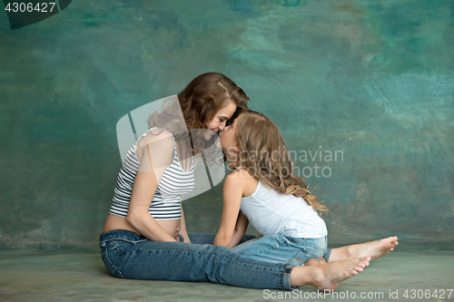 Image of Pregnant mother with teen daughter. Family studio portrait over blue background