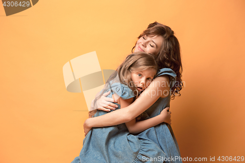 Image of Pregnant mother with teen daughter. Family studio portrait over brown background