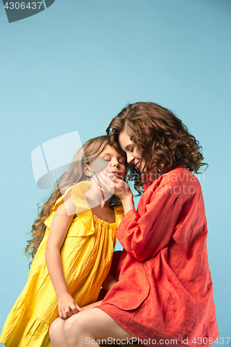 Image of Pregnant mother with teen daughter. Family studio portrait over blue background