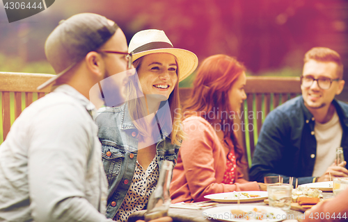 Image of happy friends having dinner at summer garden party