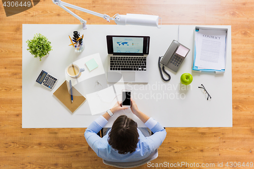 Image of businesswoman with laptop and smartphone at office