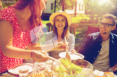 Image of happy friends having dinner at summer garden party