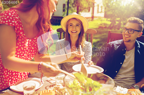 Image of happy friends having dinner at summer garden party