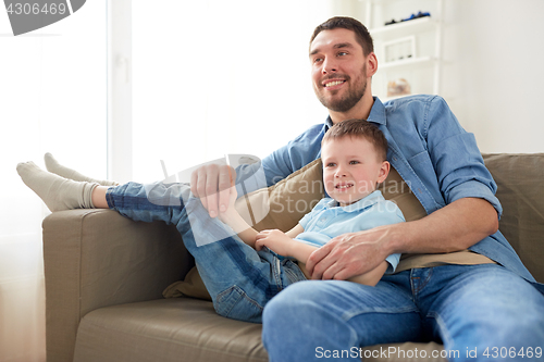 Image of happy father and son sitting on sofa at home