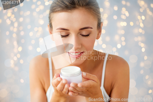 Image of close up of happy woman holding and smelling cream