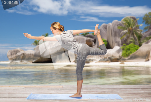 Image of woman doing yoga lord of the dance pose on beach