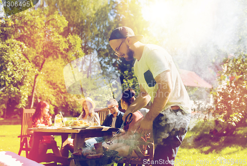 Image of man cooking meat on barbecue grill at summer party