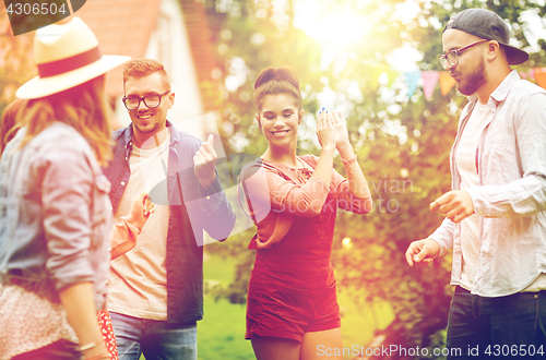 Image of happy friends dancing at summer party in garden