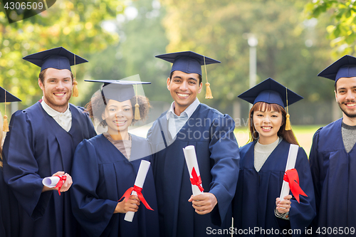 Image of happy students in mortar boards with diplomas