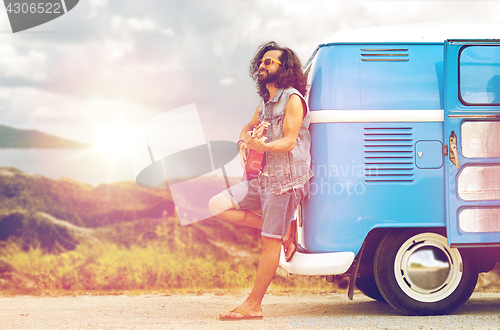 Image of hippie man playing guitar at minivan car on island