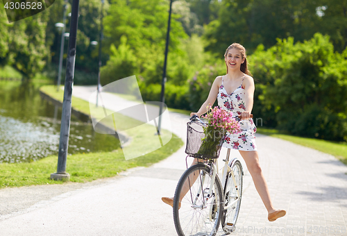 Image of happy woman riding fixie bicycle in summer park