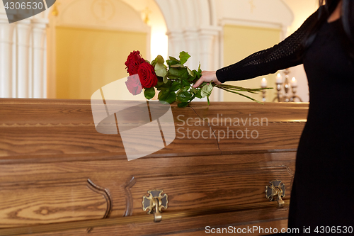 Image of woman with red roses and coffin at funeral