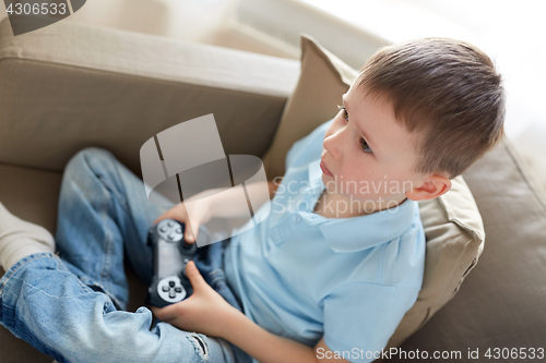 Image of little boy with gamepad playing video game at home