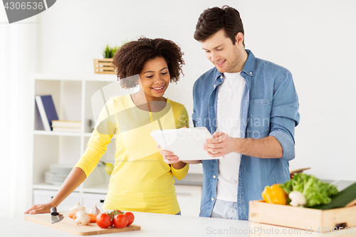 Image of happy couple with tablet pc cooking food at home