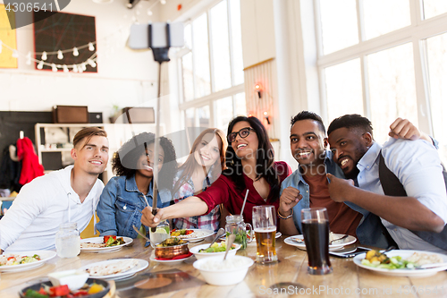 Image of friends eating and taking selfie at restaurant