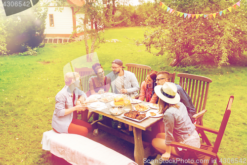 Image of happy friends having dinner at summer garden party