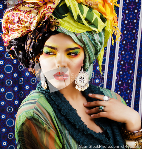 Image of beauty bright woman with creative make up, many shawls on head l