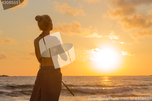 Image of Woman practicing yoga on sea beach at sunset.