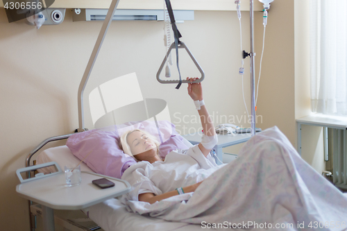 Image of Bedridden female patient recovering after surgery in hospital care.