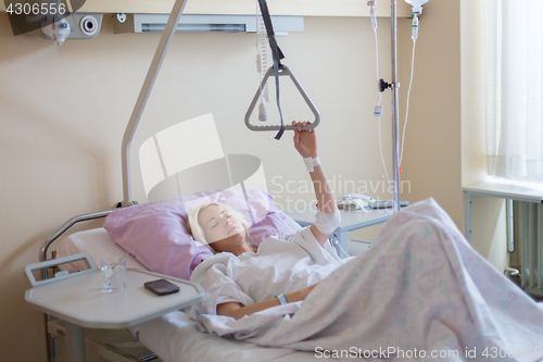 Image of Bedridden female patient recovering after surgery in hospital care.