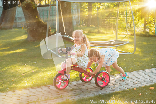 Image of Cute little blond girls riding a bicycle in summer.