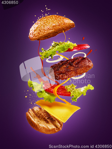 Image of The hamburger with flying ingredients on lilac background