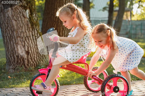 Image of Cute little blond girls riding a bicycle in summer.