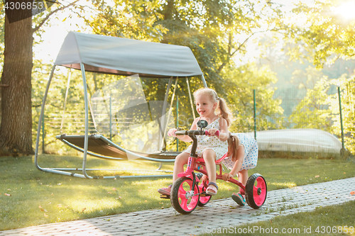 Image of Cute little blond girls riding a bicycle in summer.