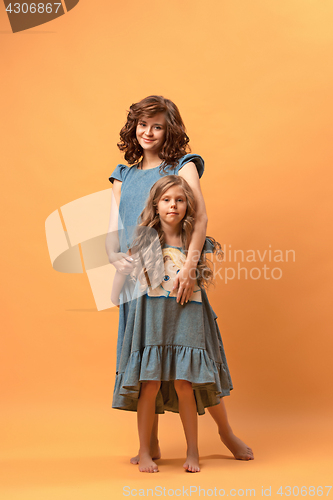 Image of Pregnant mother with teen daughter. Family studio portrait over brown background