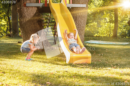 Image of Happy little girls rolling down the hill on the playground