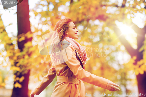 Image of beautiful happy young woman walking in autumn park