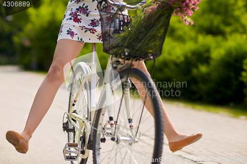 Image of happy woman riding fixie bicycle in summer park