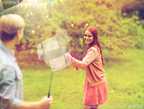 Image of happy friends playing badminton at summer garden