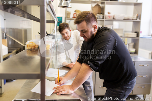 Image of chef and cook with grocery list at kitchen