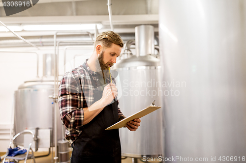 Image of man with clipboard at craft brewery or beer plant