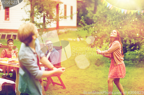 Image of happy friends playing badminton at summer garden