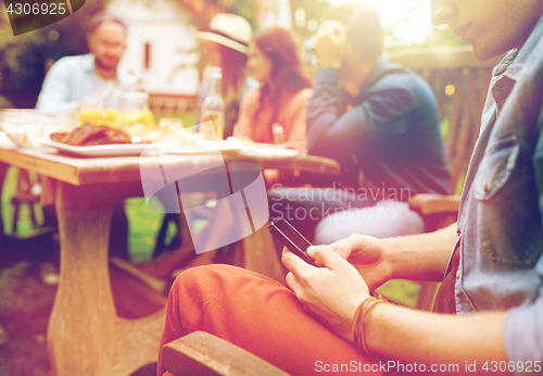 Image of man with smartphone and friends at summer party
