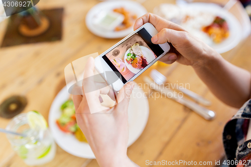 Image of hands with smartphone picturing food at restaurant