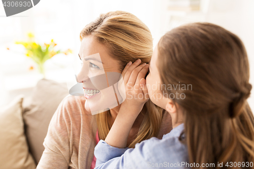 Image of happy girl whispering secret to her mother at home