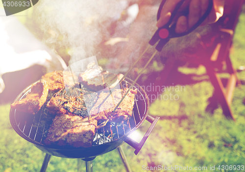 Image of man cooking meat on barbecue grill at summer party
