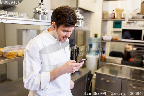 Image of chef cook with smartphone at restaurant kitchen