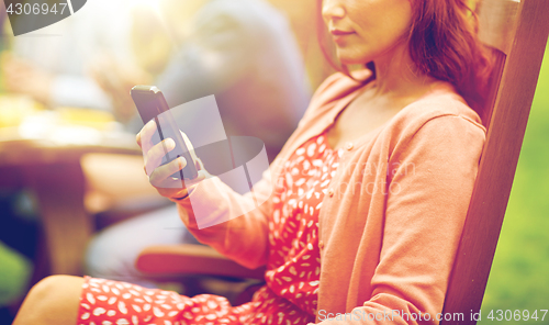 Image of woman with smartphone and friends at summer party