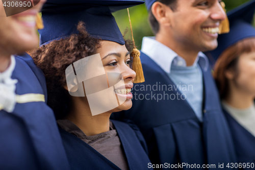 Image of happy students or bachelors in mortar boards