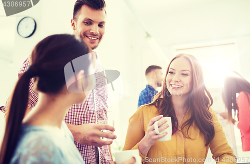 Image of happy creative team drinking coffee at office