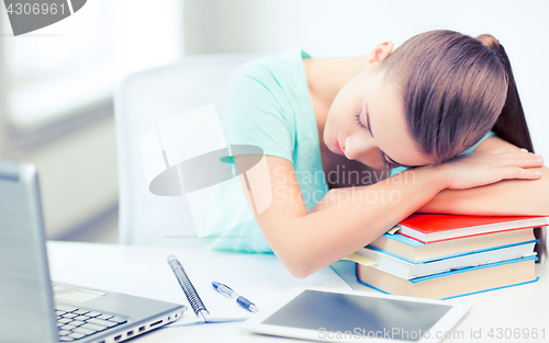 Image of tired student sleeping on stock of books