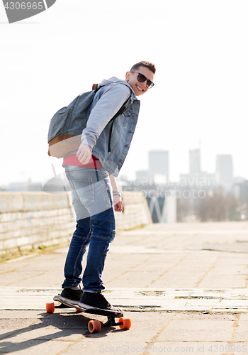 Image of happy young man or teenage boy riding on longboard