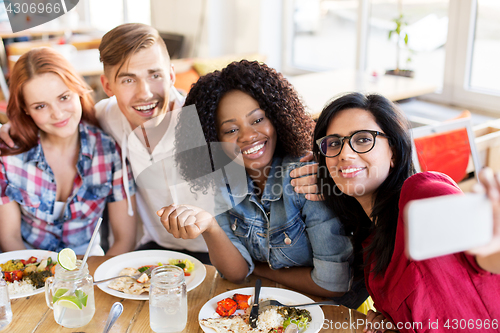 Image of friends eating and taking selfie at restaurant